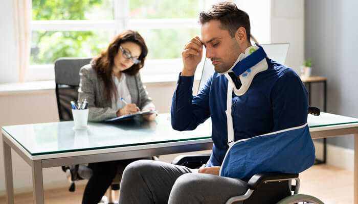 Medical evidence | tycoonstory media Person in a wheelchair with visible injuries discussing medical evidence for a long-term injury claim with a lawyer.