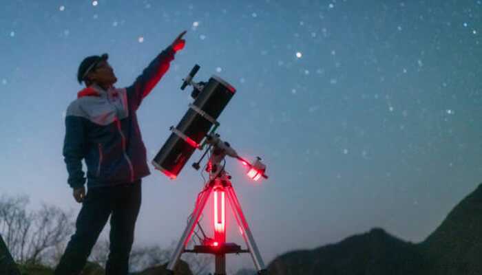Navigating the night sky | tycoonstory media A person using a celestron starsense explorer telescope under a starry sky, pointing toward a constellation.