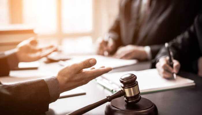 Outlining compensation expectations during consultations | tycoonstory media Legal consultation for workplace accidents—close-up of hands gesturing during a discussion with a gavel on the table, symbolizing legal proceedings and compensation claims.