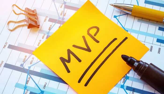 Psychological tricks to make your mvp irresistible - tycoonstory | tycoonstory media A close-up shot of a yellow sticky note with the handwritten acronym mvp for investors underlined twice, placed on top of financial data sheets with a pen, marker, and paperclip.