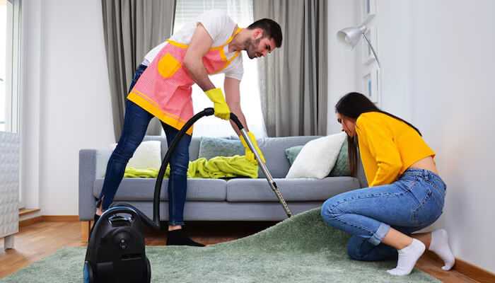 Remove allergens to create a healthier home | tycoonstory media A couple lifting a carpet and vacuuming underneath as part of their weekly deep cleaning routine to maintain a tidy and allergen-free home.