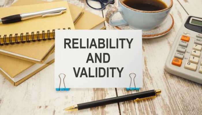 Rv | tycoonstory media Reliability and validity sign on a desk with a pen, notebook, coffee cup, and calculator, related to behavioural assessment tools.