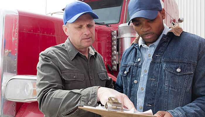 Truck lane restrictions | tycoonstory media Two truck drivers discussing documentation in front of a florida truck, highlighting the importance of florida trucks regulations.