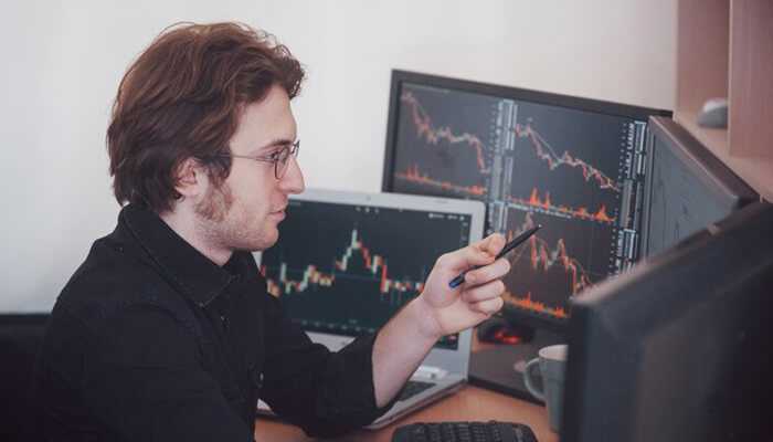 Where technical analysis falls short | tycoonstory media Trader analyzing multiple monitors showing market charts and order flow data for real-time trading decisions.