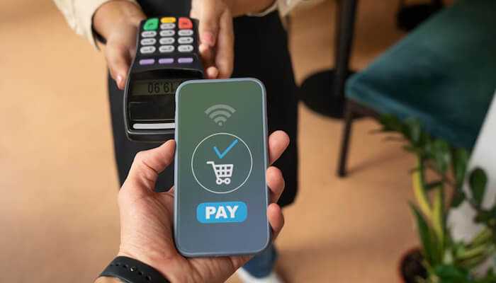 Wide range of payment options | tycoonstory media A person making a secure mobile payment using a smartphone at a point-of-sale terminal, representing the convenience of modern digital transactions through payment gateways.
