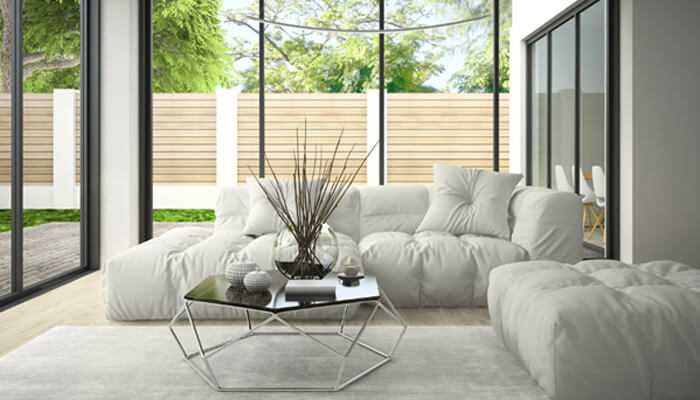 1 | tycoonstory media A minimalist living room with a white couch and a sleek metal-framed coffee table top with a glass, creating a clean, contemporary aesthetic.
