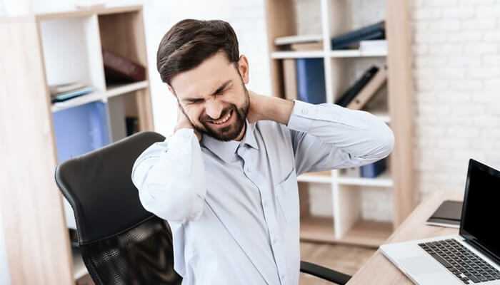 1chronic pain and disability | tycoonstory media Businessman suffering neck pain at office desk — chronic discomfort from untreated whiplash consequences