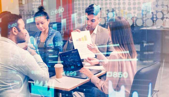 1salesforce implementation services | tycoonstory media Team analyzing business charts and metrics on laptops and papers, representing data integration and analytics through salesforce implementation services.