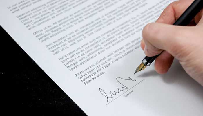 A crucial element for long-term success | tycoonstory media Close-up of a person signing a contract, representing the legal and formal process involved in corporate mergers and acquisitions.