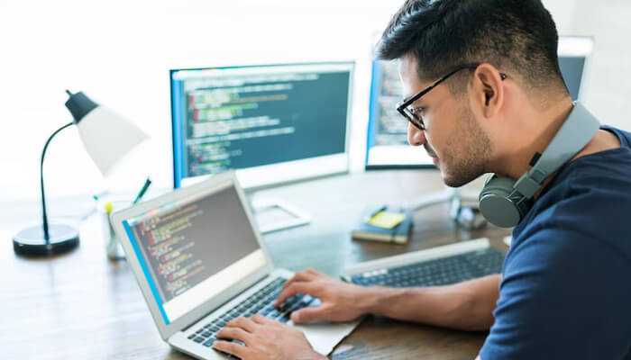 Aa 1 | tycoonstory media Man working on code with headphones, showcasing cheap web development practices on multiple screens.
