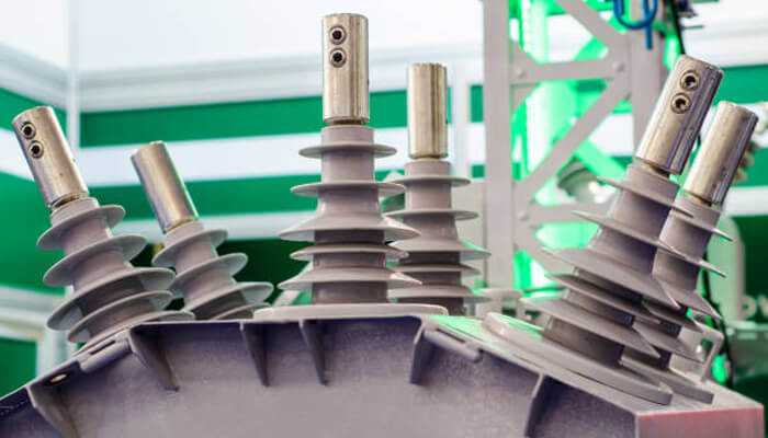 Advantages of deploying reclosers in electrical grids | tycoonstory media Close-up view of high-voltage components of a recloser unit used in electrical grids, showcasing its insulators and terminals for improving grid reliability.