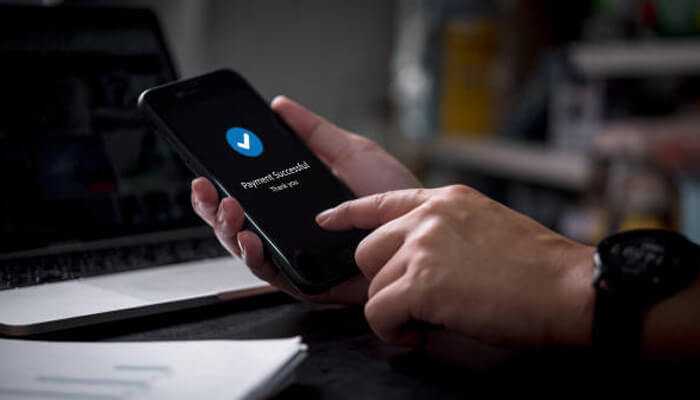 Avoid missing payments | tycoonstory media Managing student loans with a mobile phone displaying a successful payment confirmation to avoid missing payments.