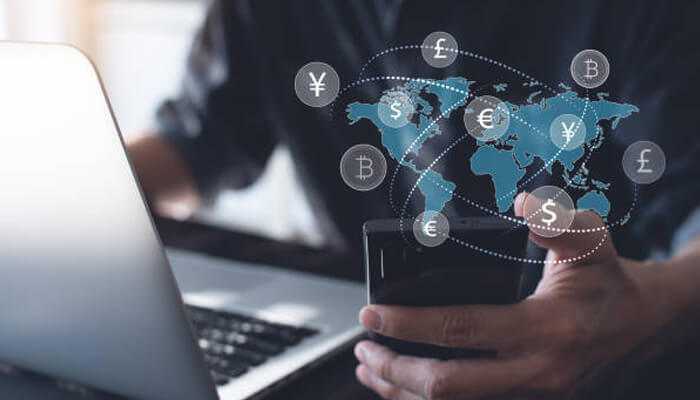 Benefits for travelers and businesses | tycoonstory media Mobile and laptop displaying global currency icons, illustrating cryptocurrency in travel industry for international bookings and payments.