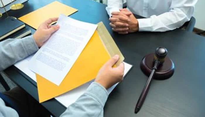 Breaches of trademark agreements | tycoonstory media A trademark lawyer reviewing legal documents with a client during a consultation on trademark agreement breaches, with a gavel on the table.