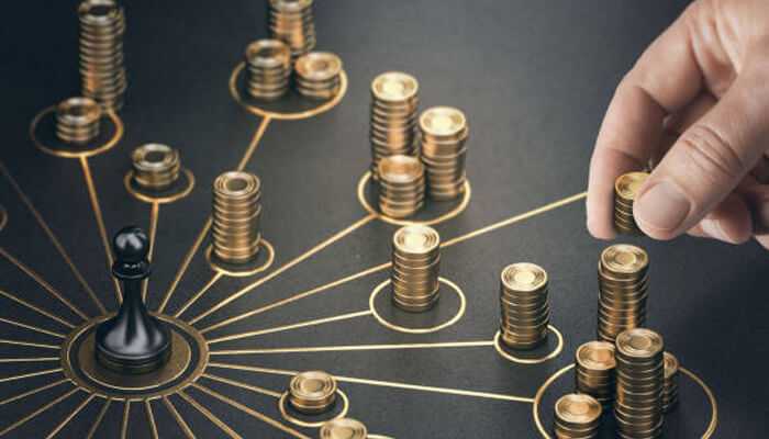 Build multiple income streams | tycoonstory media Hand placing gold coins on a strategic board game with multiple stacks representing different investment options, illustrating the concept to diversify your net worth.