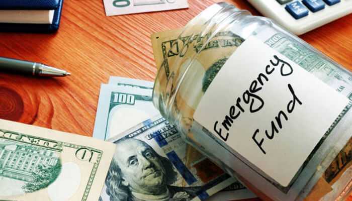 Emergency fund | tycoonstory media A jar labeled'Emergency Fund' with cash, highlighting the importance of building an emergency fund to prevent financial mistakes during unexpected expenses.
