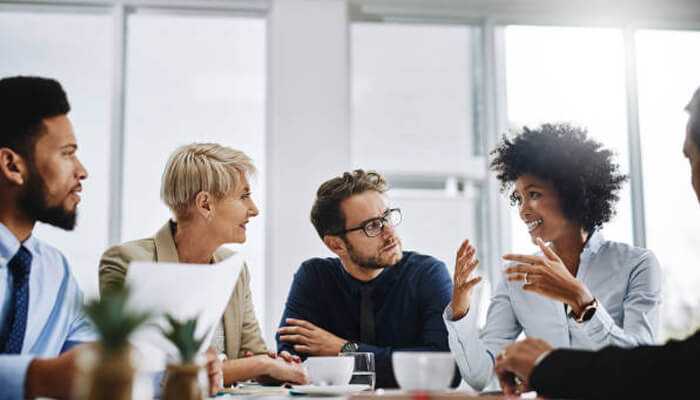 Foster strong team communication | tycoonstory media Team collaborating actively in a meeting, demonstrating strong communication and teamwork as part of effective project management hacks in 2025.