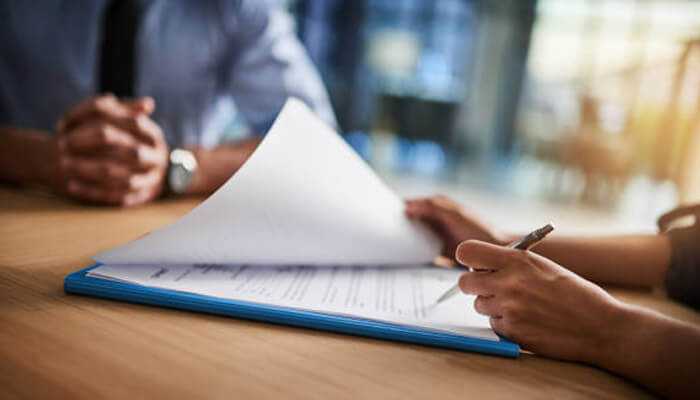 Insurance | tycoonstory media Close-up of two people reviewing and signing documents on a clipboard, representing the process of applying for family term insurance.