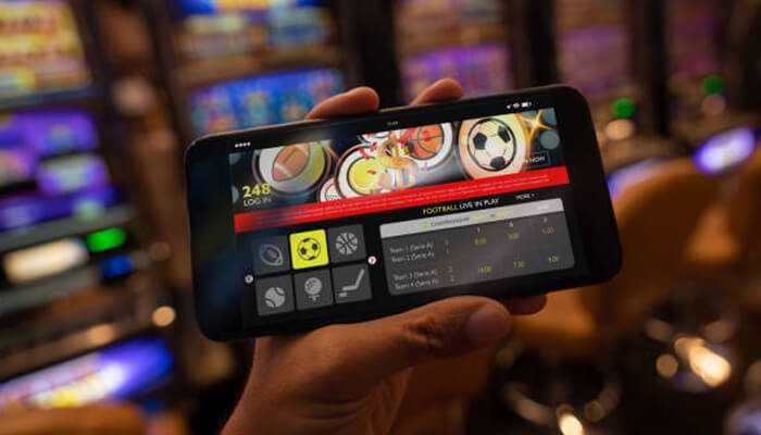 Live casino games are the new standard | tycoonstory media A person using a smartphone to place sports bets, representing the shift from traditional casinos to digital arenas through mobile gambling platforms.