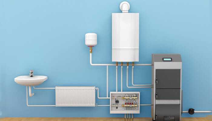 Qw | tycoonstory media Indoor hot water system setup featuring a boiler, radiator, and connected plumbing lines installed against a blue wall for household water heating.