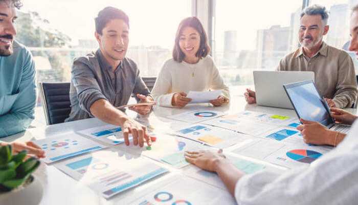 Strategic planning makes all the difference | tycoonstory media Team collaborating around a table covered with marketing charts and graphs, discussing the hidden costs of free marketing strategies.