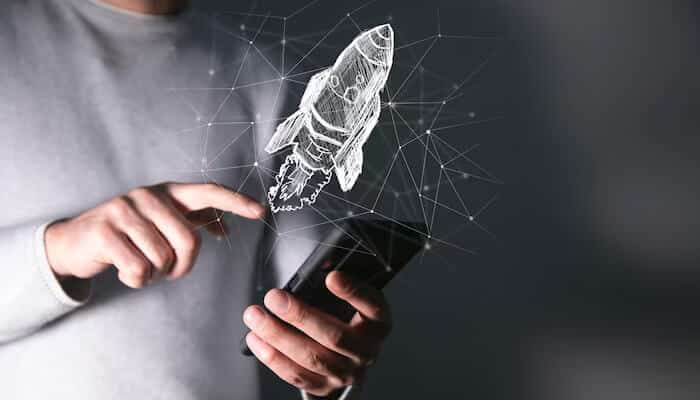 The rise of space startups | tycoonstory media Person holding a smartphone with a holographic rocket launch illustration above it, representing innovation and technology in space consulting for startups.
