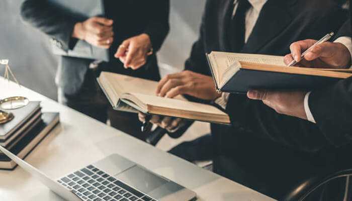 The role of legal planning in startup resilience | tycoonstory media Team of personal injury lawyers consulting legal books and working on case strategy around a laptop—highlighting expert legal planning.