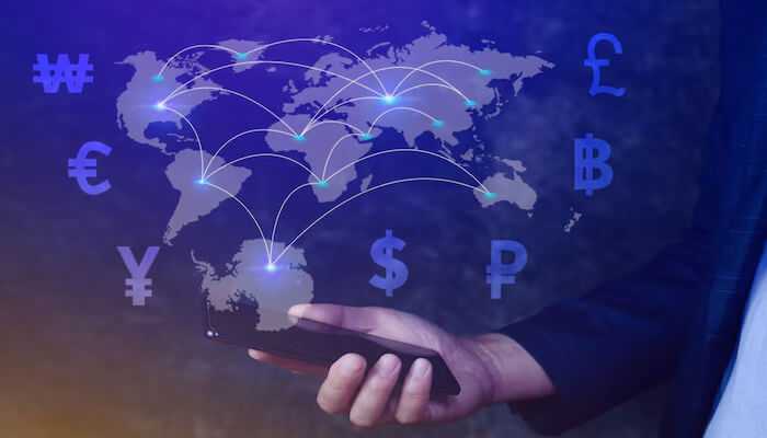 To manage currency risk you can use a combination of these methods | tycoonstory media Hand holding a smartphone with a world map and currency symbols overlaid, representing global financial connectivity and currency risk management strategies.