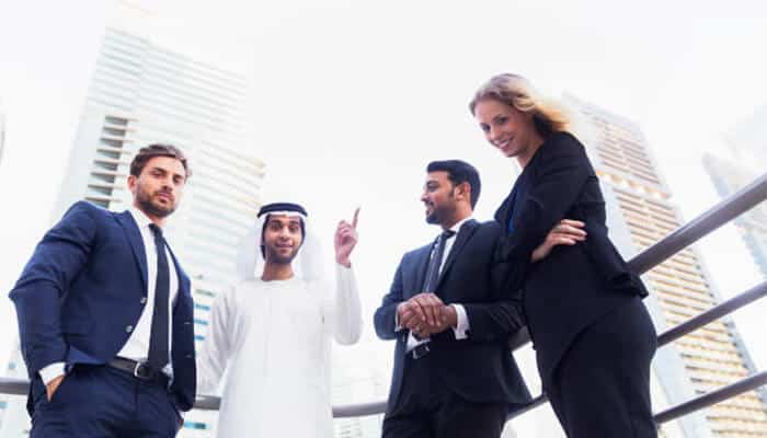 Top 10 real estate brokers in dubai | tycoonstory media Group of professional real estate brokers in dubai discussing a business deal outdoors with modern skyscrapers in the background.