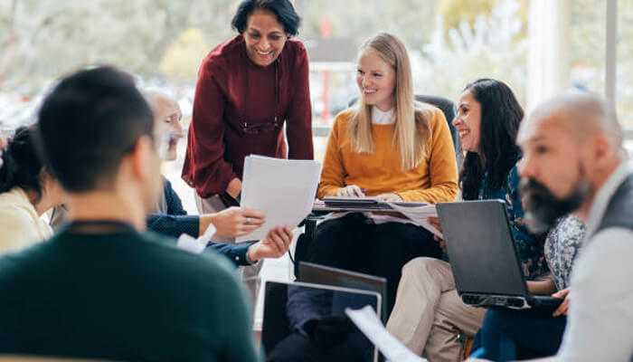 Understanding the role of usha | tycoonstory media A diverse group of professionals engaged in a collaborative meeting, discussing documents and working together on a project aligned with usha's mission of improving healthcare access and equity.