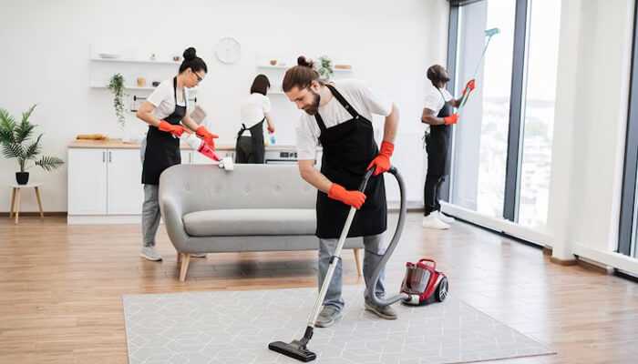 What affects end of lease cleaning cost | tycoonstory media End of lease cleaning in progress with professional cleaners vacuuming, wiping surfaces, and deep cleaning a furnished apartment before tenant move-out.