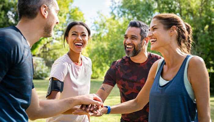 A diverse group of friends bonding after exercise in a park, illustrating how awareness is redefining wellness through community support, movement, and joyful connection.