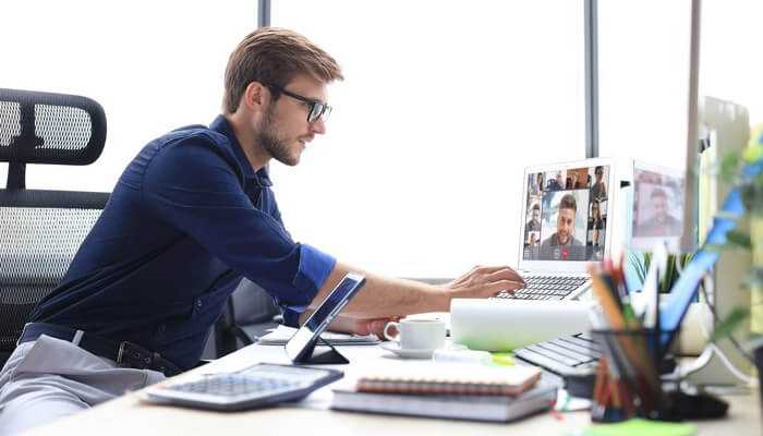 Access to global talent at competitive rates | tycoonstory media Professional engaged in a virtual interview or team call on his laptop, showcasing the remote hiring process in a modern work environment.