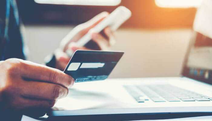 Expanding choice increases trust and conversions | tycoonstory media Person using a credit card and smartphone for an online purchase on a laptop, illustrating the role of secure payments in boosting online sales.