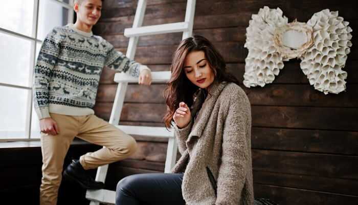 Good cashmere | tycoonstory media A young couple in cozy winter clothing, including cashmere clothing, standing in a modern indoor space with wooden walls, a white ladder, and a unique shell art piece.
