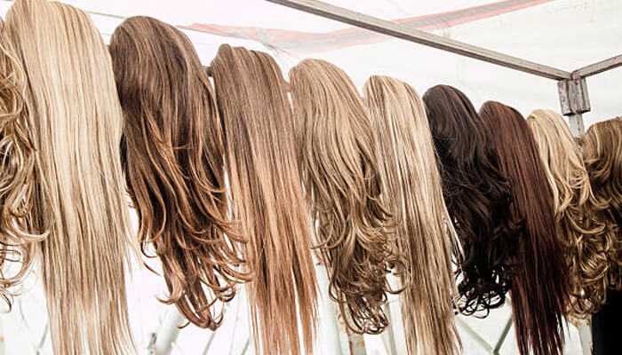 Hair drawstring wigs | tycoonstory media A variety of human hair drawstring wigs in different shades and styles neatly displayed on mannequin stands in a wig shop.