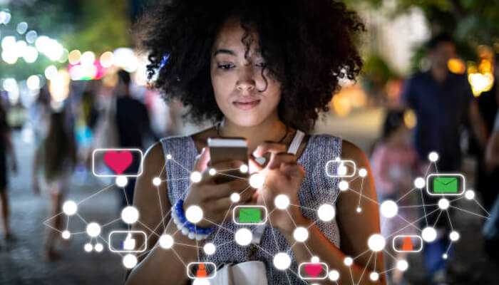 How algorithms work | tycoonstory media A young woman using her phone in a vibrant, illuminated setting, with social media icons floating around her, symbolizing the impact of social media algorithms on online engagement.
