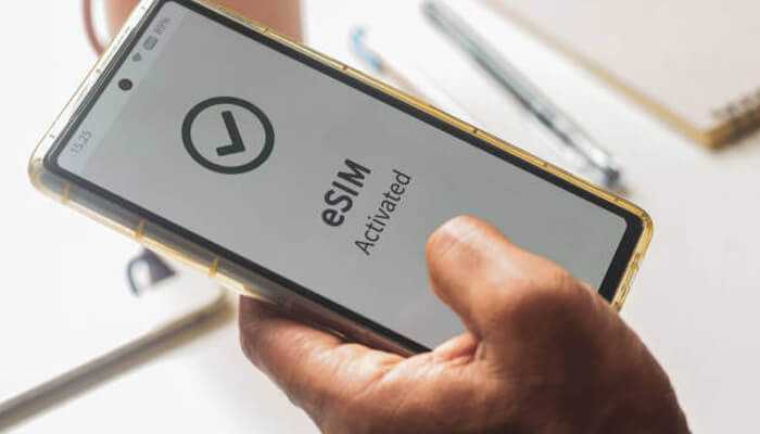 How to get free international data using esim | tycoonstory media Esim for free international data: person holding a smartphone showing'eSIM Activated' on the screen