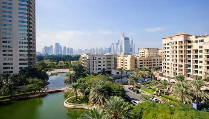 Location vs livability | tycoonstory media Serene residential community in dubai with lush greenery and skyline views in the background — a prime opportunity to buy off-plan in dubai.