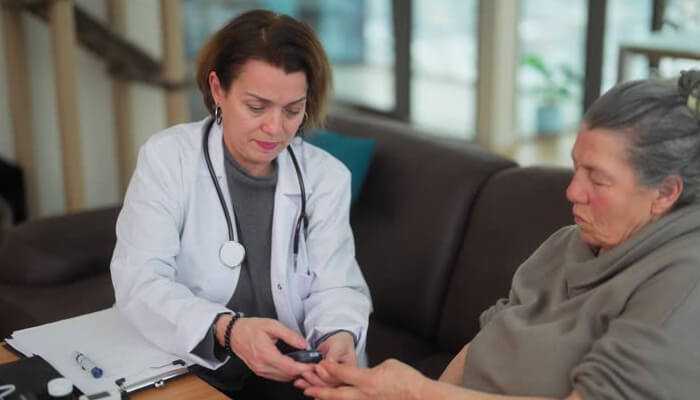 Treatment is a skill you have to build 1 | tycoonstory media A doctor carefully checking the blood sugar levels of a chronic patient at home, emphasizing attentive care and management for chronic patients.