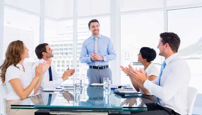 Who founders listen to when it counts | tycoonstory media A group of employees applauding a founders who is giving a presentation, highlighting the recognition and leadership of the founder in the team.