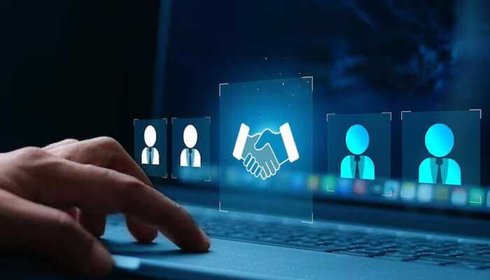 Why buying engagement makes sense | tycoonstory media A hand interacting with a laptop screen showing digital icons of people and a handshake, symbolizing the process of buying engagement through online platforms or digital agreements.