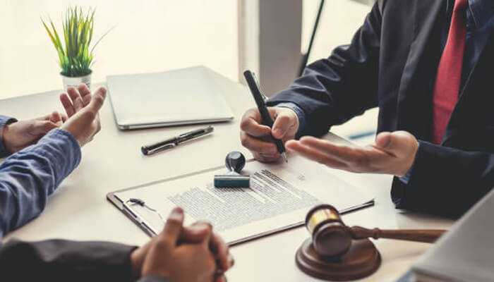 Working with a professional expert witness | tycoonstory media Accident attorneys discussing legal documents and case details with clients during a personal injury consultation.