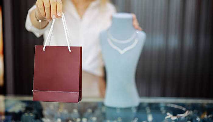 Rare carat Customer holding a shopping bag in a jewelry store with a diamond necklace on display, representing rare carat's modern diamond shopping experience.