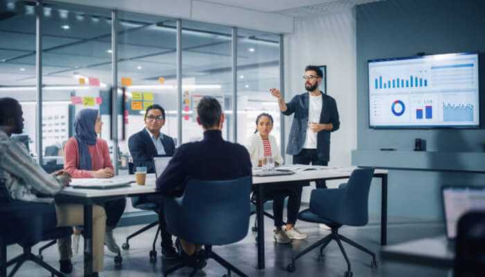 Choosing the right channel manager for increasing occupancy rate 1 | tycoonstory media Business team in a meeting, presenting data analysis and insights on hotel occupancy rates in a modern office setting.
