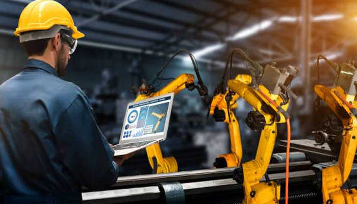 Consistent quality via automation integration | tycoonstory media Engineer managing robotic automation on a factory floor, illustrating how welding to warehousing innovations drive smart operations.