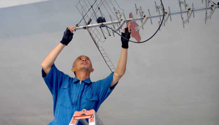 Factors affecting signal strength | tycoonstory media Professional conducting indoor tv aerials installation, aligning the antenna for best signal quality.