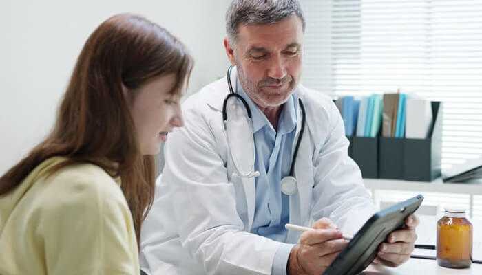 Health insurance options | tycoonstory media A doctor and patient discussing health insurance options, possibly related to west virginia health insurance, with a digital tablet in the doctor's hand showing relevant information.