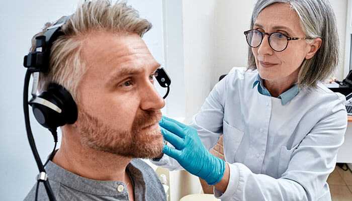 Hearing loss - tycoonstory | tycoonstory media Healthcare professional performing a hearing test to detect occupational diseases like workplace-related hearing loss.