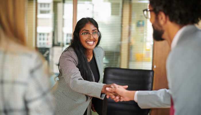 Internal ta teams have a broad focus | tycoonstory media Executive assistant greeting a new colleague with a handshake in a corporate office setting.